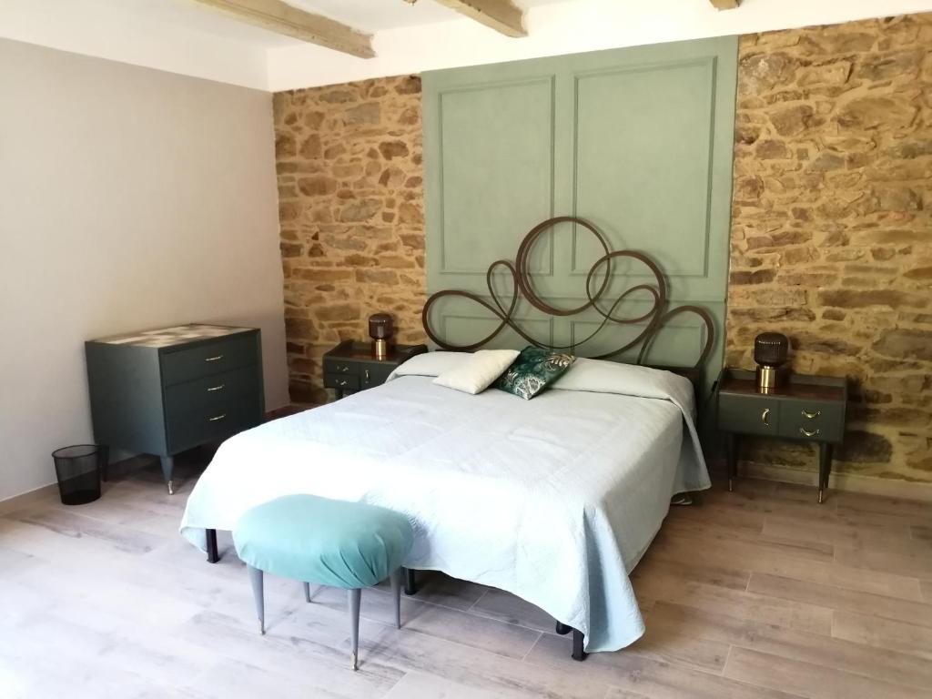1 dormitorio con 1 cama grande y pared de piedra en Casale Santa Margherita, en Bucine