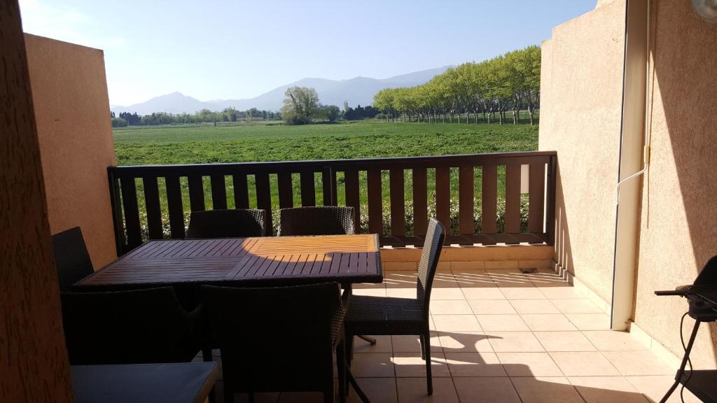 d'une table et de chaises sur un balcon avec vue sur un champ. dans l'établissement LES EMBRUNS - SPACIEUX APPARTEMENT AVEC PISCINE, à Saint-Cyprien