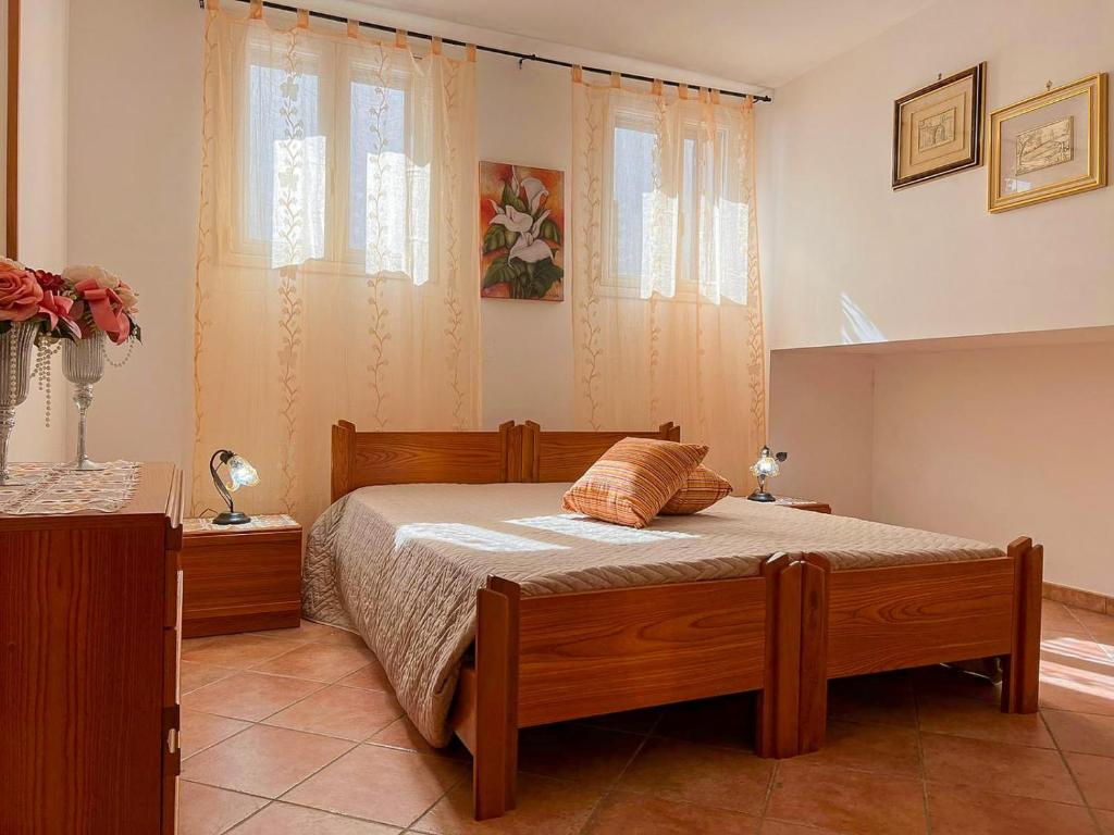 マリーナ・ディ・マンカヴェルサにあるCasa Vacanza MANCAVERSAのベッドルーム1室(木製ベッド1台、窓2つ付)