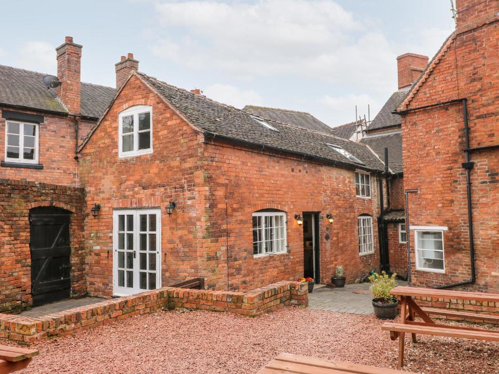 un edificio de ladrillo con un banco delante de él en Buttercross Cottage, en Rugeley