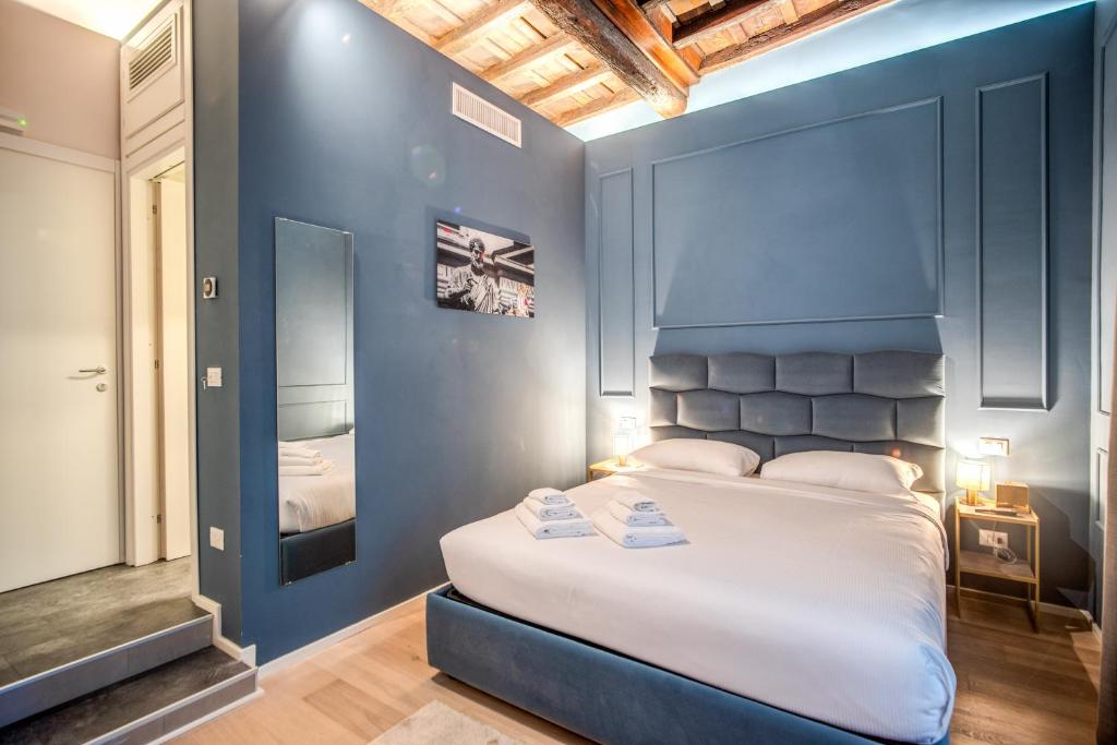 a bedroom with a large bed with a blue wall at Capranica Private Suites in Rome