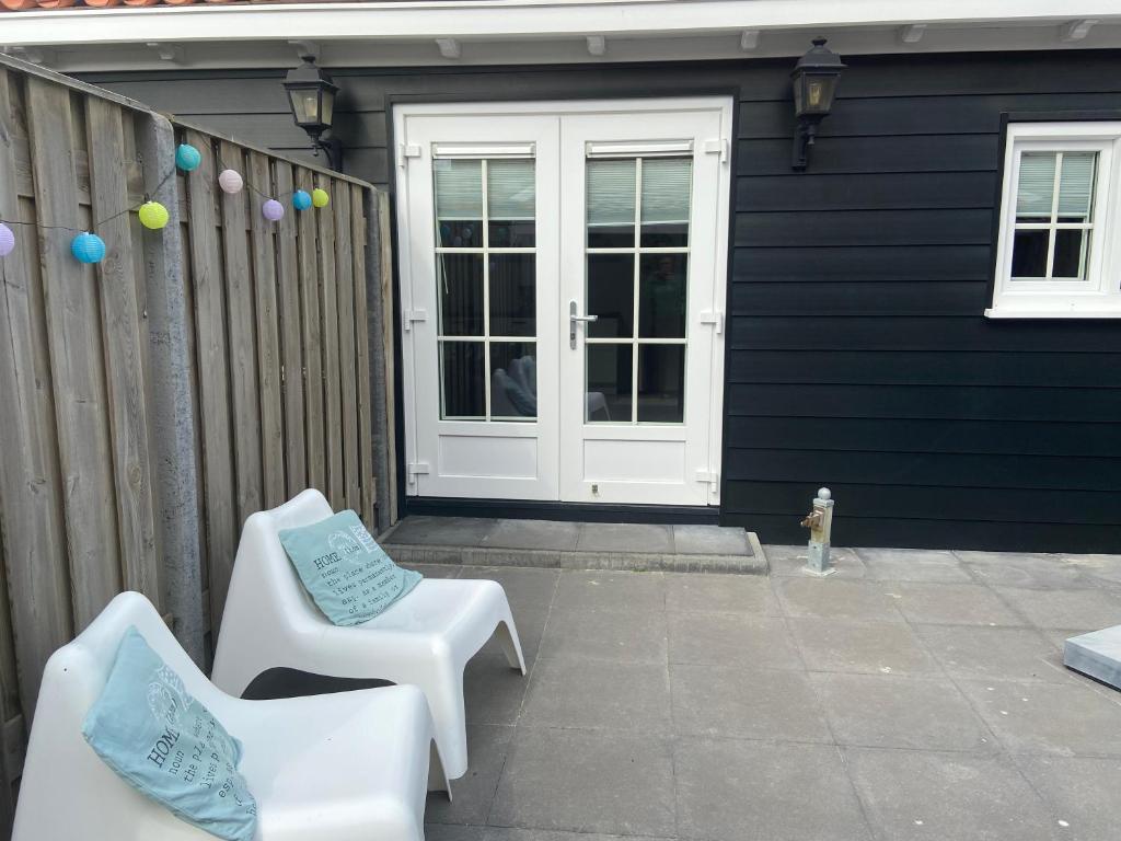 eine Terrasse mit 2 Stühlen und eine Tür mit Ballons in der Unterkunft Zon en Zee Westkapelle in Westkapelle