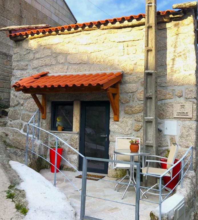 a table and chairs in front of a stone building at Casinha da Raposeira in Soajo