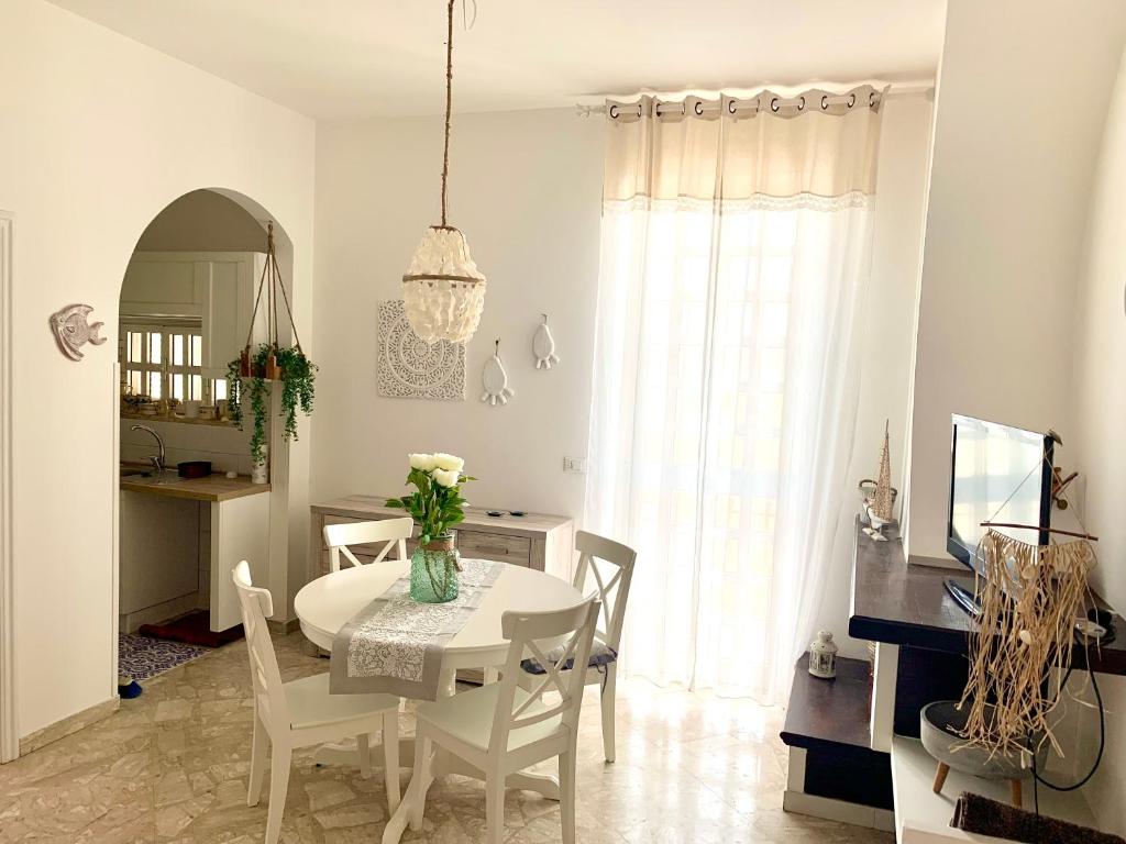 uma sala de jantar branca com uma mesa e cadeiras em Litosoru Casa Vacanze em Savelletri di Fasano