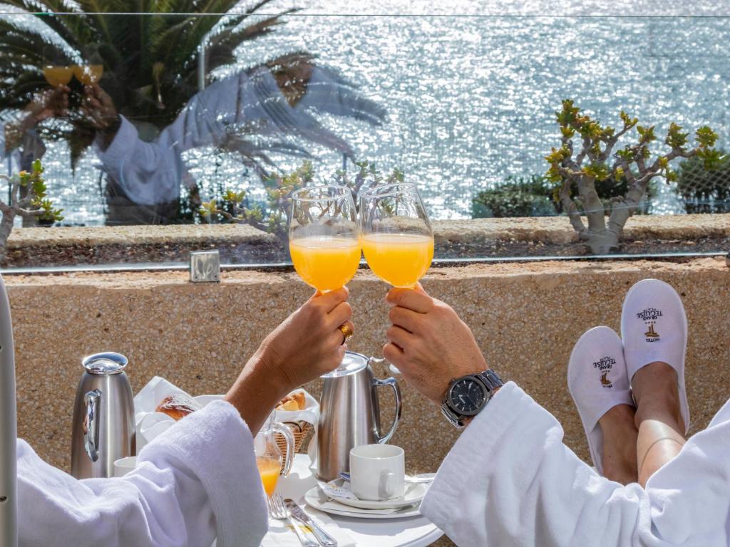 two people are holding up glasses of orange juice at Alexandre Grand Teguise Playa in Costa Teguise