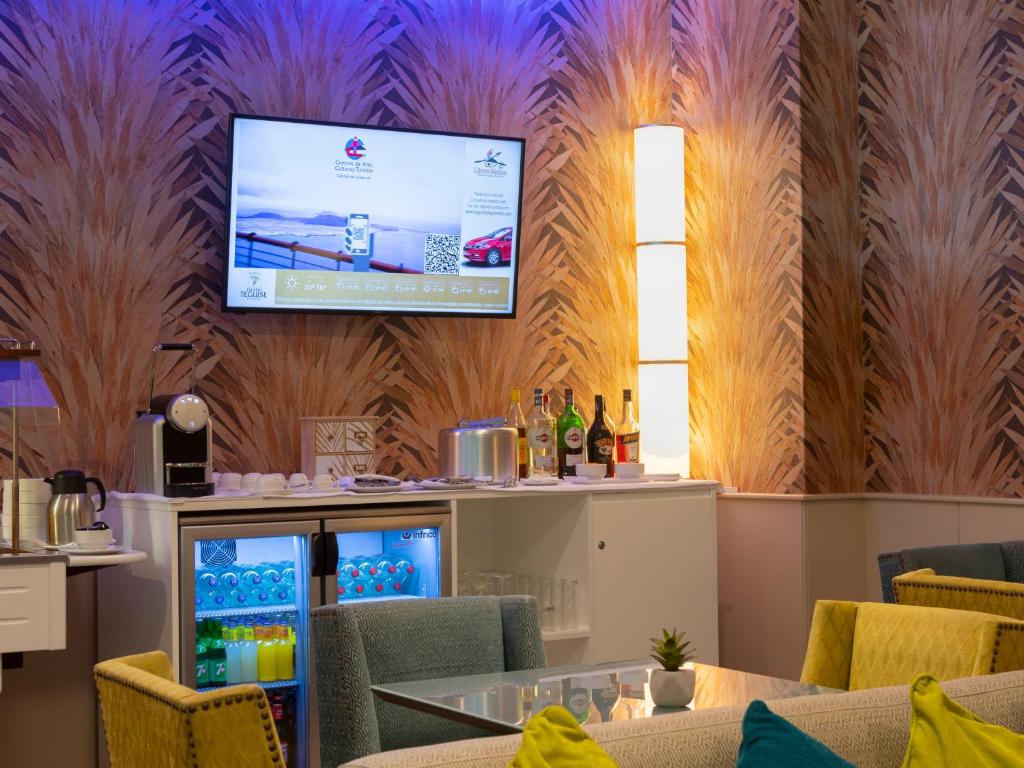 a bar with a tv hanging on a wall at Alexandre Grand Teguise Playa in Costa Teguise