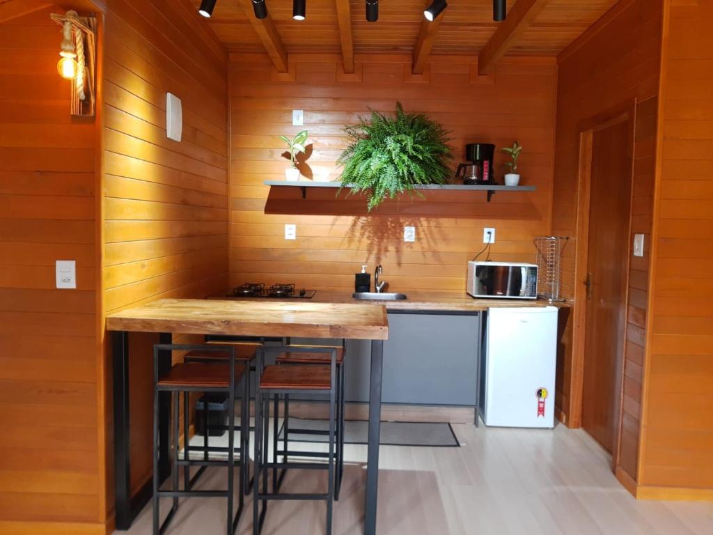 a kitchen with wooden walls and a counter with stools at Chalé Guest House in Urubici