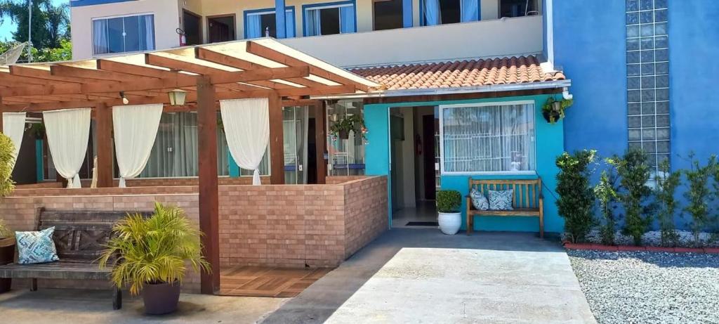 a blue house with a wooden pergola at Pousada Recanto Feliz in Penha