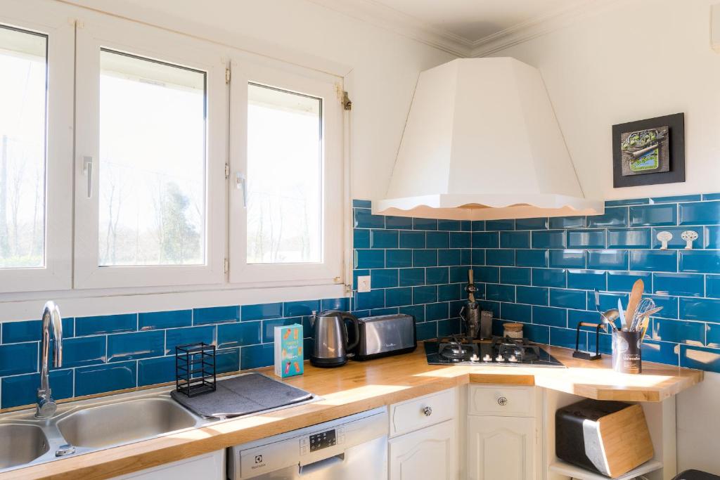 a kitchen with blue tiled walls and a sink at Jolie maison pour 8 personnes in Plobannalec-Lesconil
