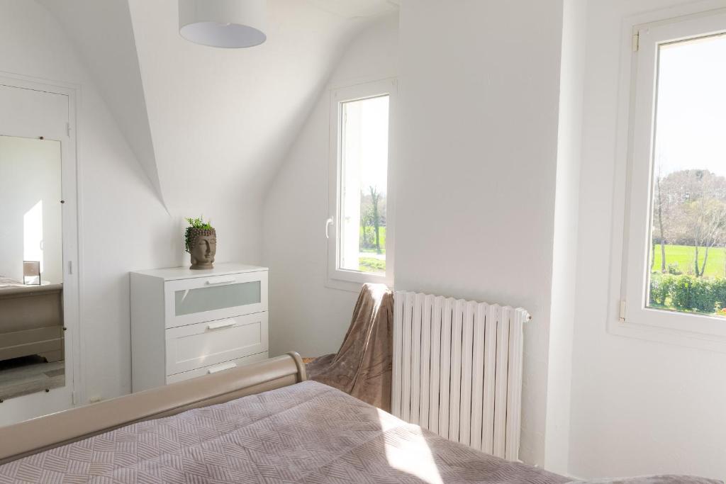 a white bedroom with a bed and a window at Jolie maison pour 8 personnes in Plobannalec-Lesconil