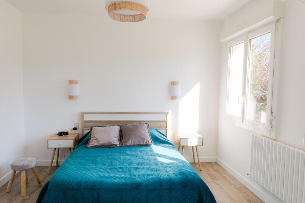 a white bedroom with a blue bed and a window at Jolie maison pour 8 personnes in Plobannalec-Lesconil
