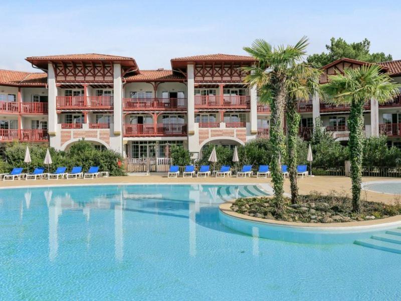un complexe avec une grande piscine en face d'un bâtiment dans l'établissement Le Domaine de Gascogne - appartement 2 pièces 4/5 personnes, à Biscarrosse