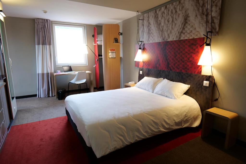 a hotel room with a bed, chair, and nightstand at ibis Moulins in Moulins
