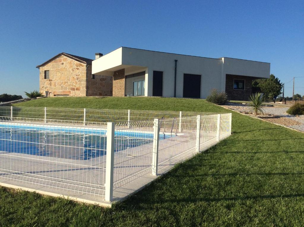 a fence around a swimming pool in front of a house at Casa do Cabeco in Seia