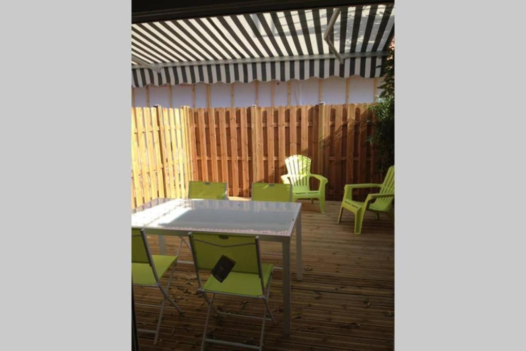 a patio with a table and chairs and a fence at Les Logis du Petit Prince in La Teste-de-Buch