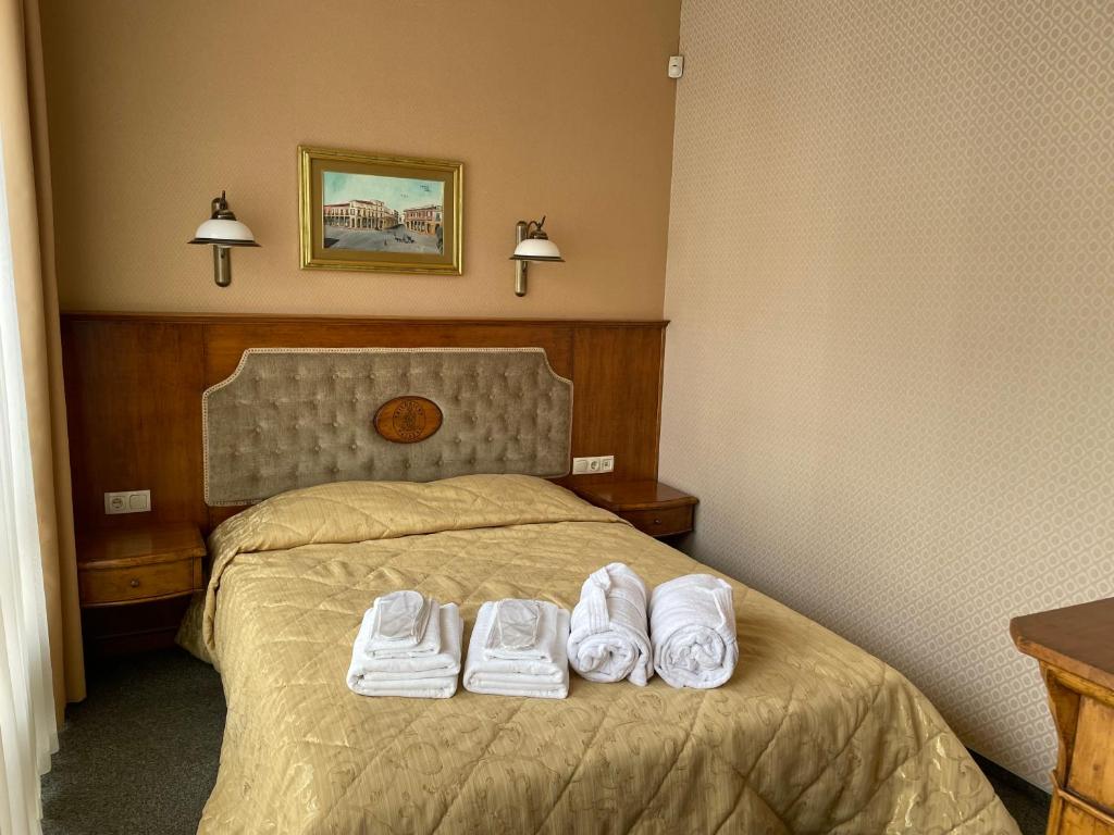 a hotel room with a bed with two pairs of shoes on it at Apartment Senamiesčio Inkaras in Klaipėda