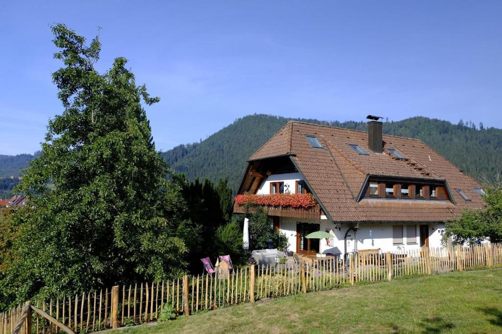 a house with a wooden fence in a field at SchwarzWild - Ferienwohnung und Ferienzimmer in Baiersbronn