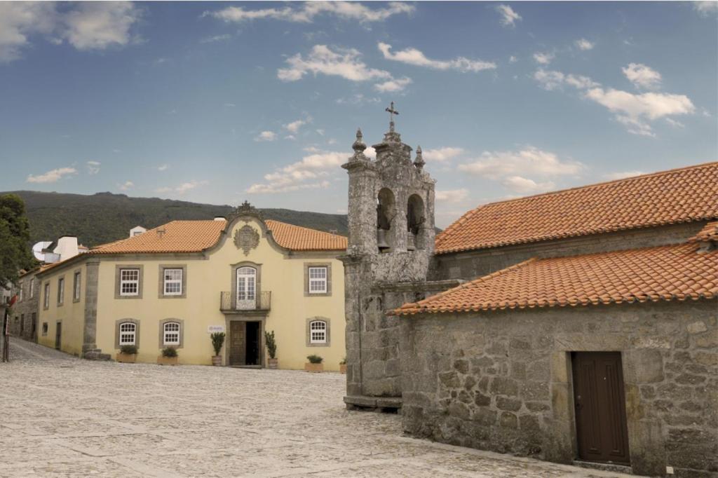 un vieux bâtiment avec une tour et une église dans l'établissement INATEL Linhares da Beira Hotel Rural, à Linhares