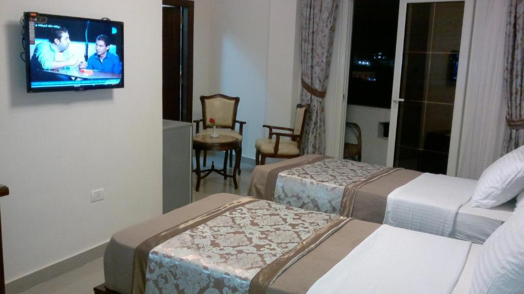 a hotel room with two beds and a tv on the wall at Abeer Hotel Alexandria in Alexandria