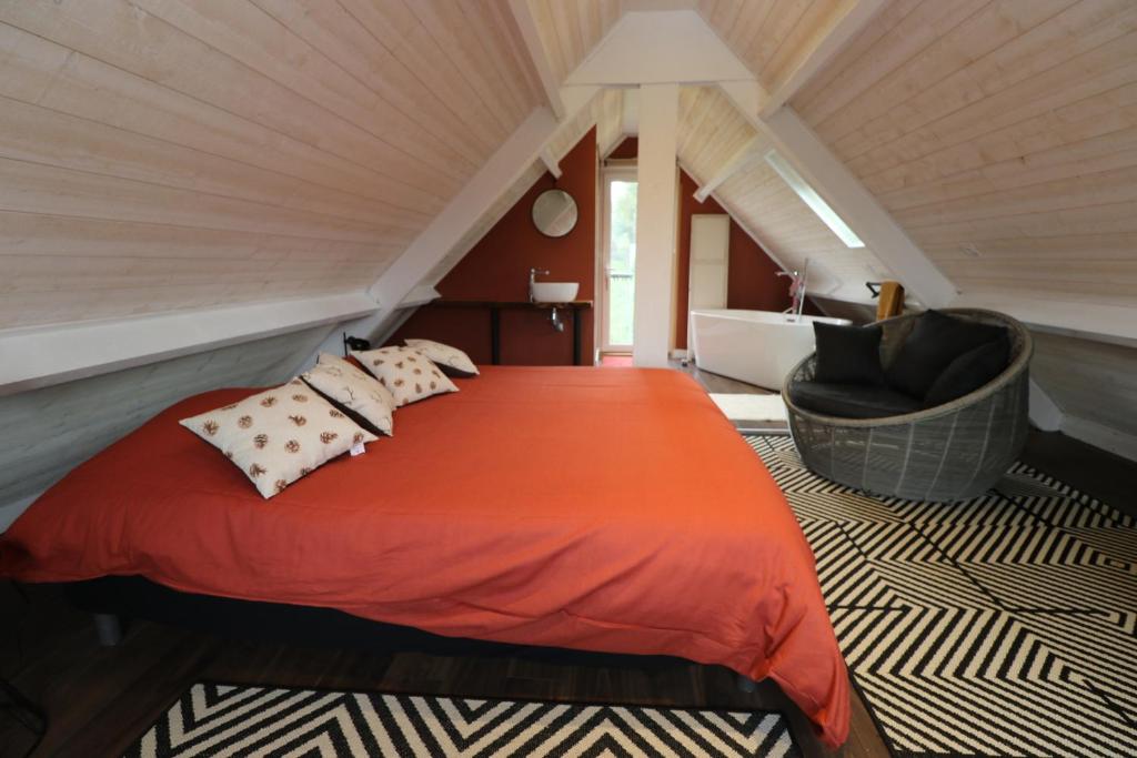 een slaapkamer met een rood bed en een stoel bij Chambre d'hôtes Boutteville in Boutteville