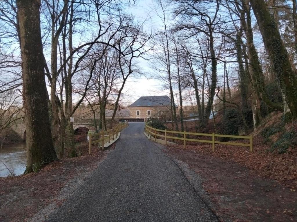 eine Straße mit einem Zaun und einem Haus in der Ferne in der Unterkunft Le Moulin De Bretigneul in Saint-Aubin-des-Landes