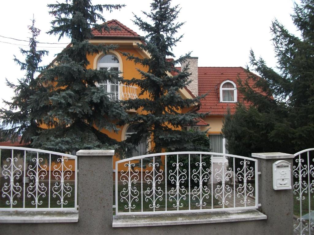 a house with a christmas tree behind a fence at Jóbor Vendégház in Győrújbarát