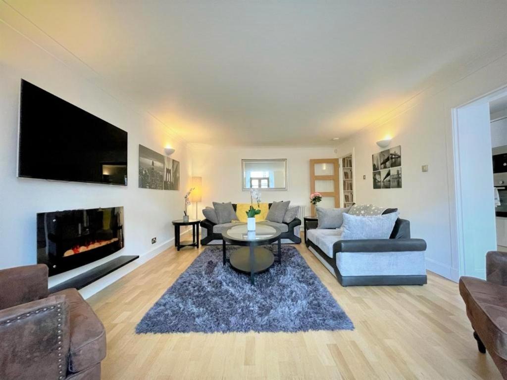 uma sala de estar com um sofá, uma mesa e uma lareira em Elite 3 Bed New Town Apt with Private Walled Garden em Edimburgo