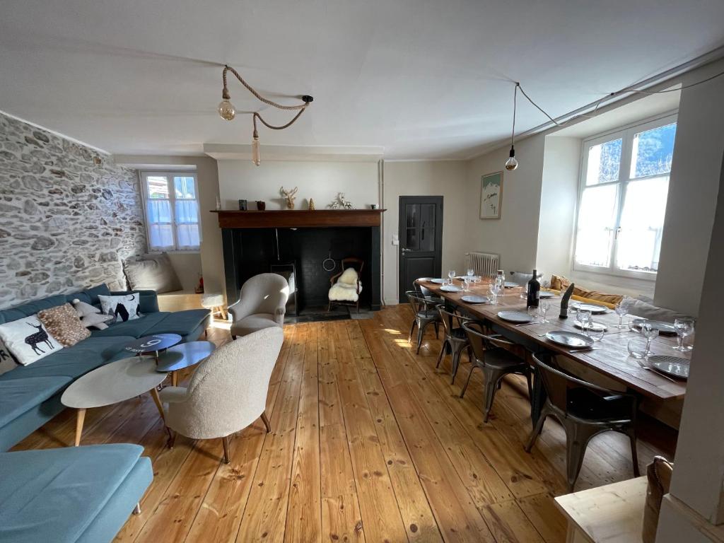 een woonkamer met een lange tafel en een open haard bij Chalet / Maison Bourgeoise entièrement rénovée in Vignec