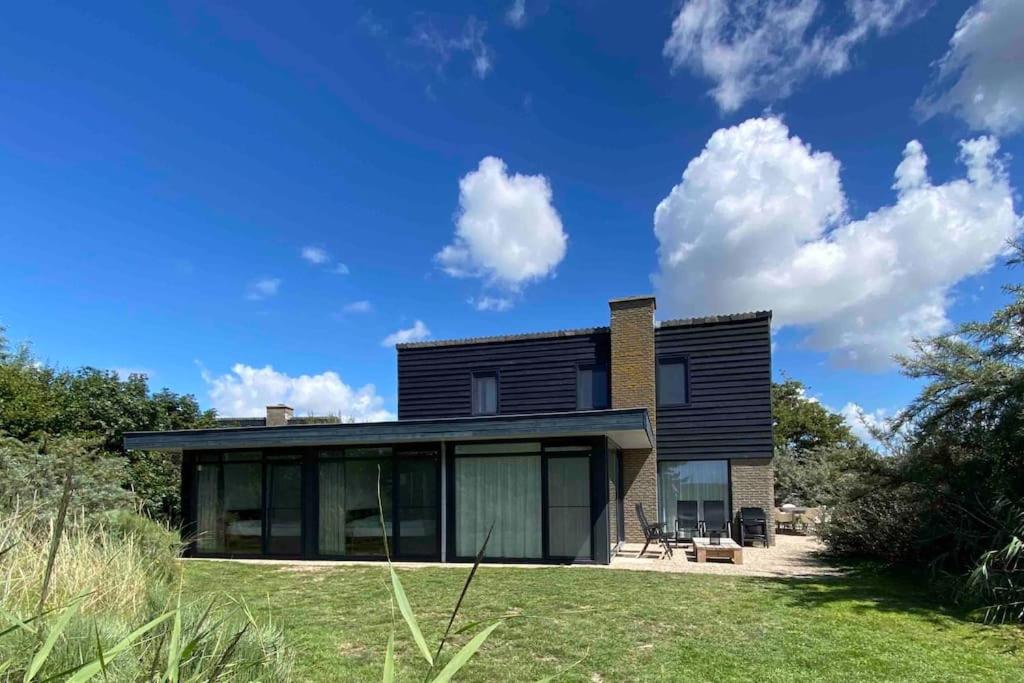a modern house with black siding and windows at Luxe 8 persoons ‘Golfvillatexel’ vlakbij zee in De Cocksdorp