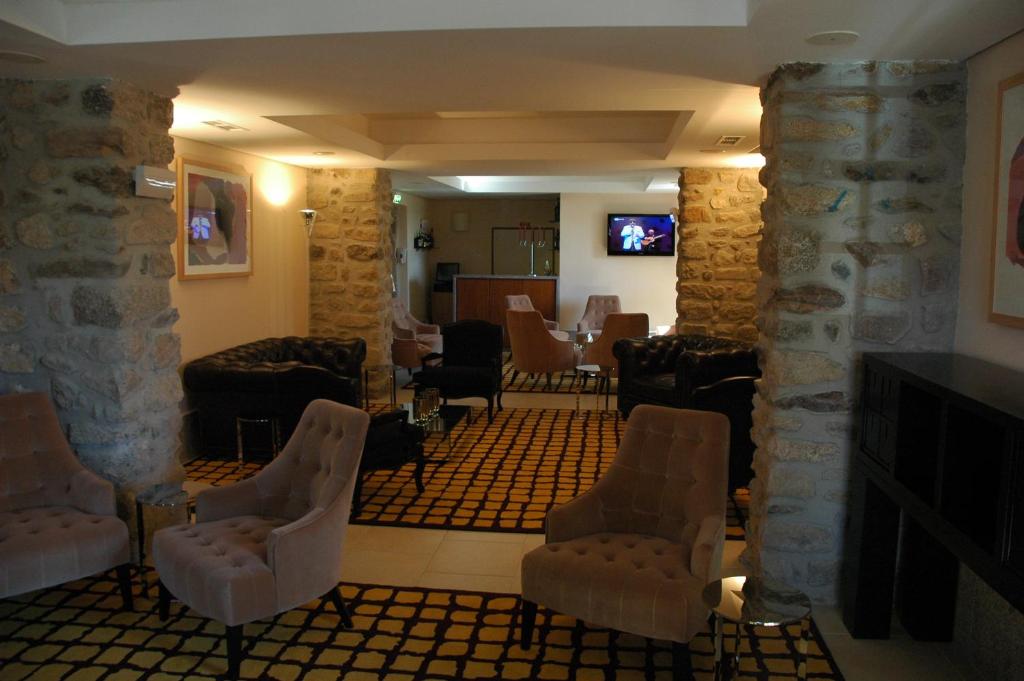 uma sala de estar com cadeiras e uma parede de pedra em INATEL Linhares da Beira Hotel Rural em Linhares