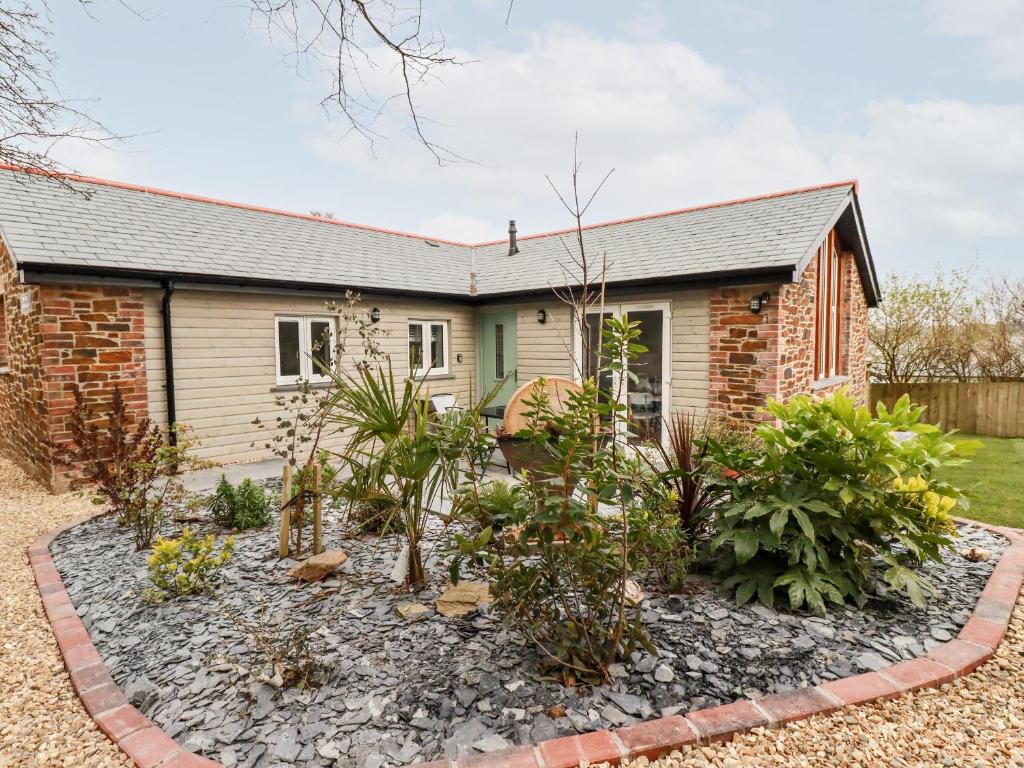 a brick house with a garden in front of it at The Old Workshop in St Austell