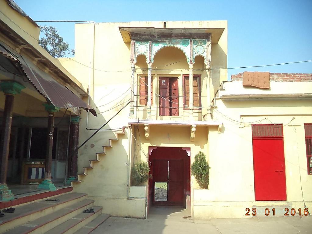 um edifício antigo com uma porta vermelha e uma escada em Shri Swami Sheetal Das Akhada B1-88 Assi , Near Pushkar Talab,Varanasi, Ashram Dharmshala em Varanasi