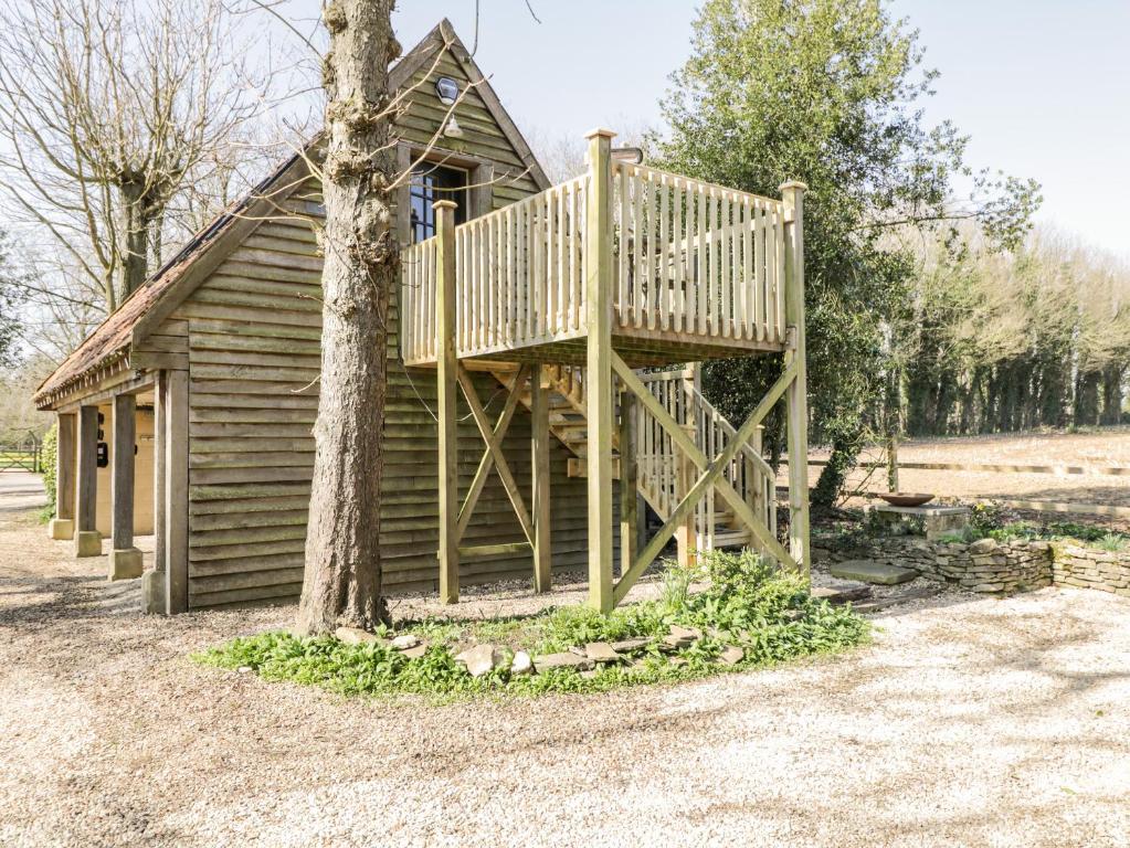 a wooden cabin with a deck next to a tree at Blue Bell in Corsham