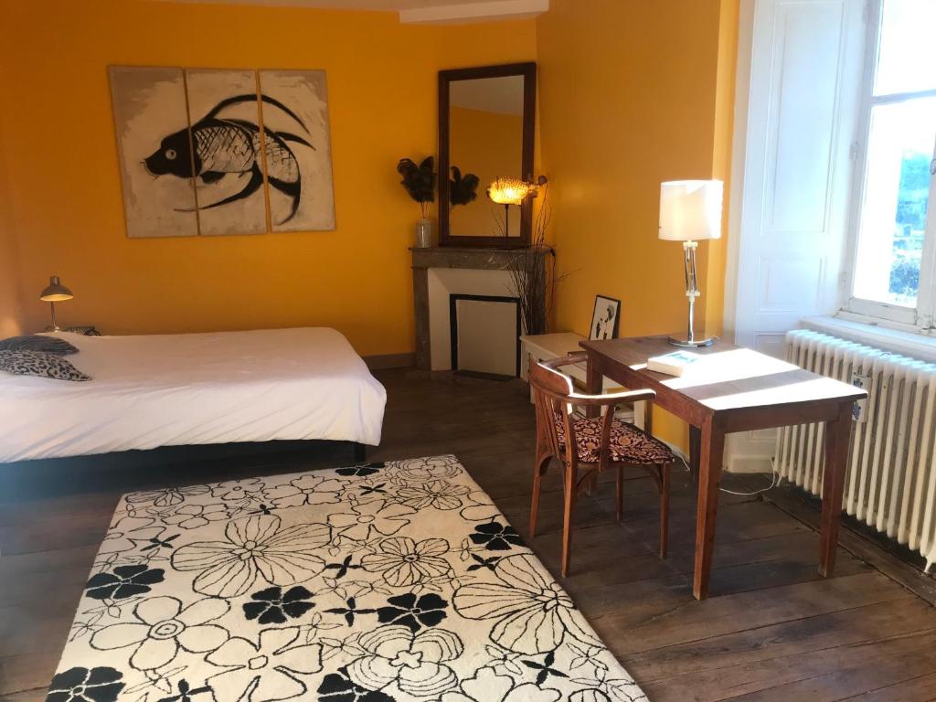 a room with a bed and a desk and a table at Maison Mercredi in Piégut-Pluviers