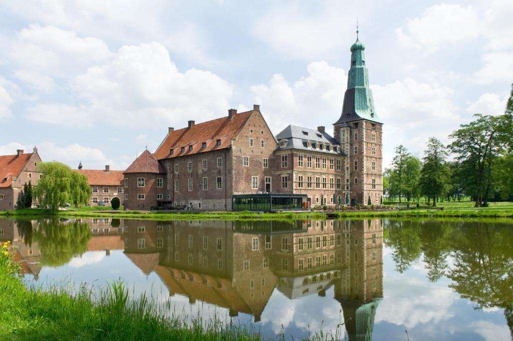 ein altes Gebäude mit Spiegelung in einem See in der Unterkunft Schloss Raesfeld in Raesfeld