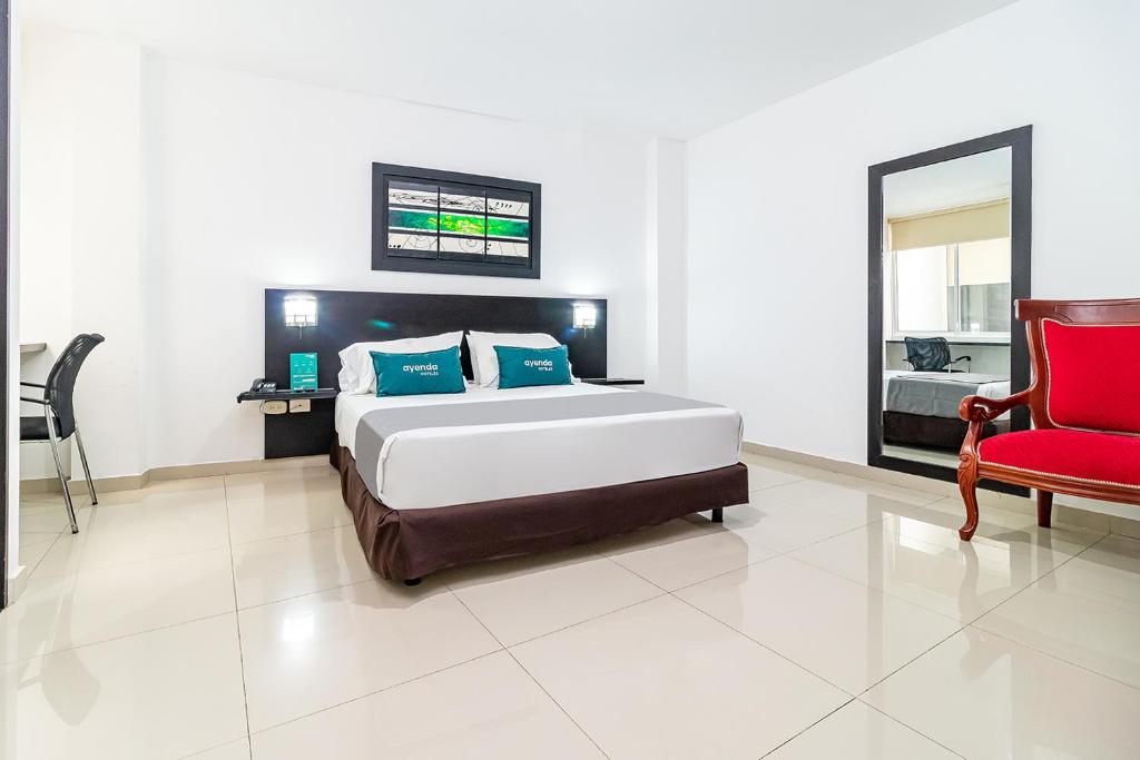 - une chambre avec un lit et une chaise rouge dans l'établissement Ayenda Quinta Estación, à Yopal