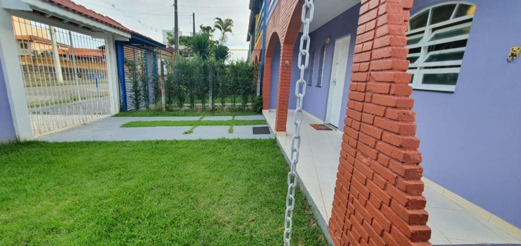una casa con césped junto a una pared de ladrillo en Sobrado no Melhor Local do Indaiá, en Caraguatatuba