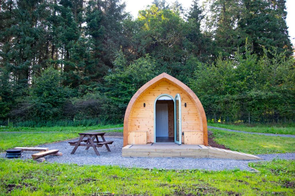 a small wooden shelter with a picnic table in a field at Luxury Rural Ayrshire Glamping Pod in Dalmellington