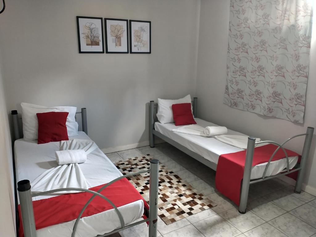 duas camas num quarto com vermelho e branco em Pousada Flor de Mãe em Volta Redonda