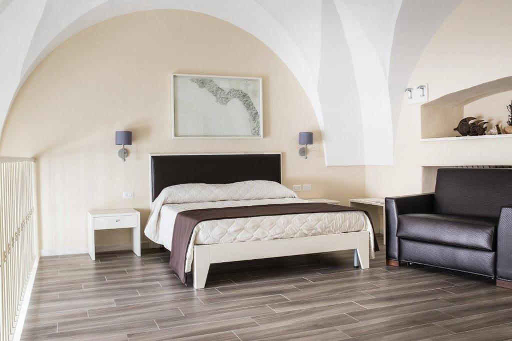 a bedroom with a bed and a chair at Faro Bianco Gallipoli Dependance in Gallipoli