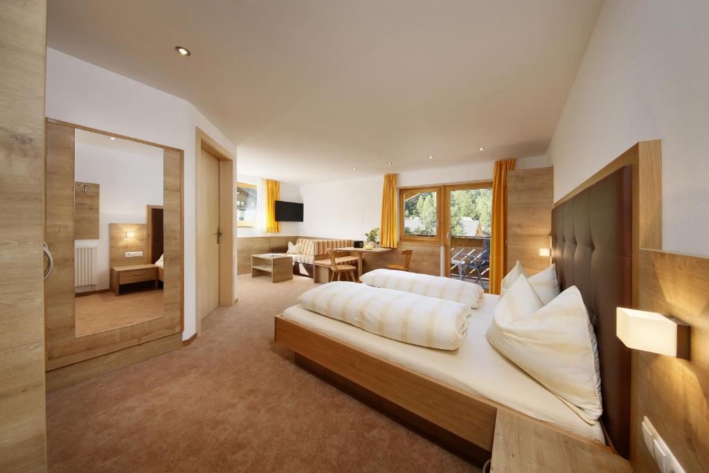a bedroom with a bed and a living room at Garni-Hotel Wiesental in Pfelders