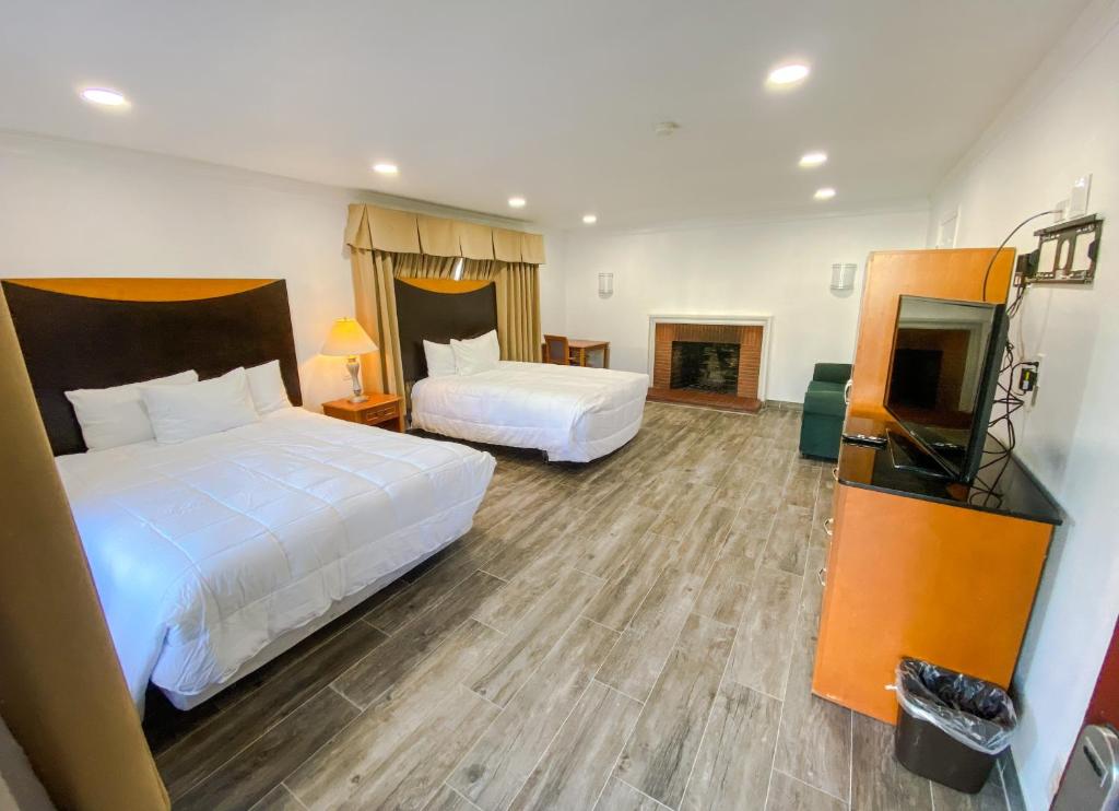 ein Hotelzimmer mit zwei Betten und einem Flachbildfernseher in der Unterkunft Town and Country Inn in Santa Barbara