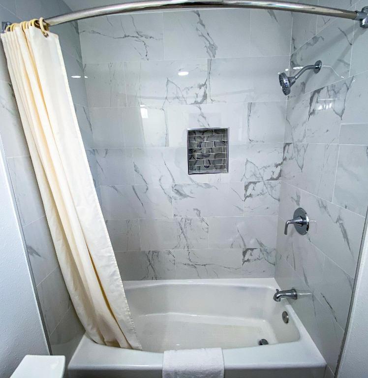 ein weißes Badezimmer mit Badewanne und Dusche in der Unterkunft Town and Country Inn in Santa Barbara