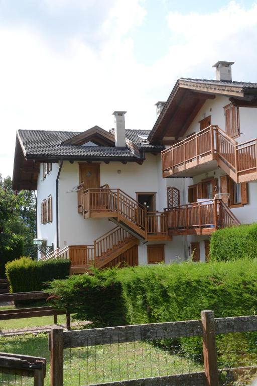 a house with wooden balconies and a fence at Santi’s Apartment in Folgaria