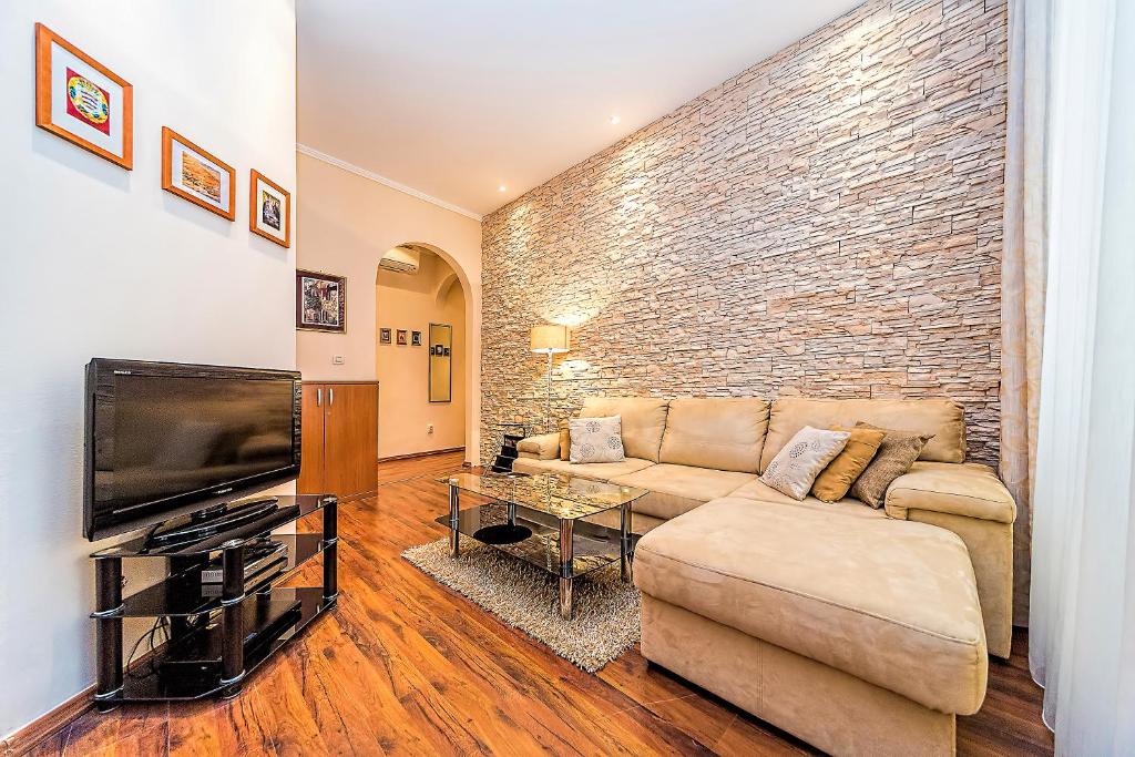 Apartment La Petite في دوبروفنيك: غرفة معيشة مع أريكة وجدار من الطوب