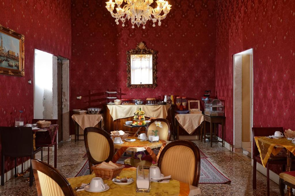 a dining room with red walls and tables and a chandelier at Residenza Hotel San Maurizio in Venice