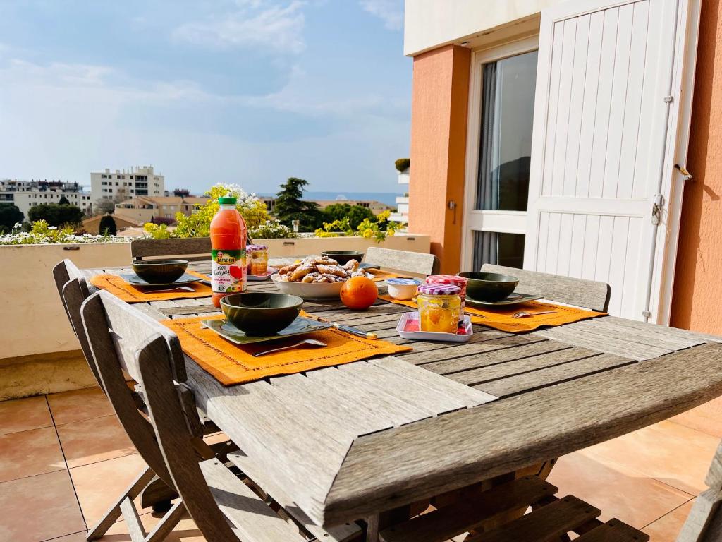 einen Holztisch mit Essen auf dem Balkon in der Unterkunft Marseille 8ème - T3, 4 couchages, terrasse - proche plage in Marseille