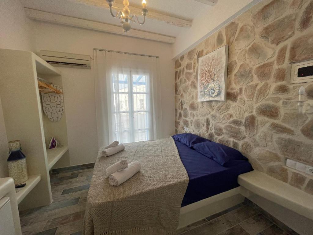 a bedroom with a bed and a stone wall at BURGOS BARRIO in Naxos Chora