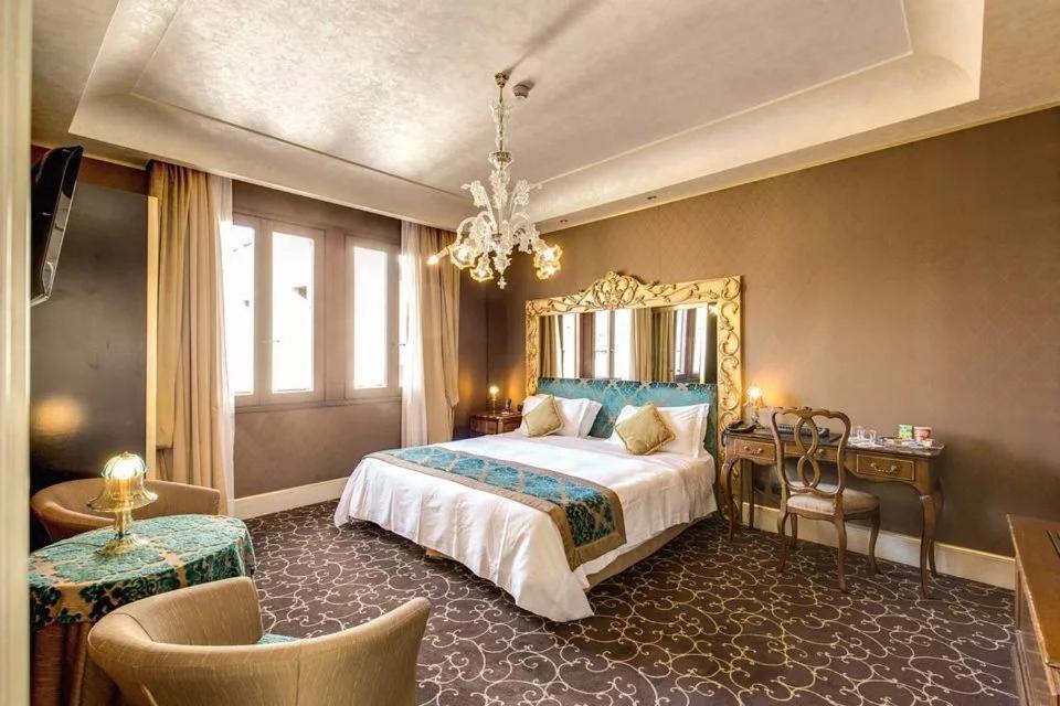 a bedroom with a large bed and a chandelier at Pesaro Palace in Venice