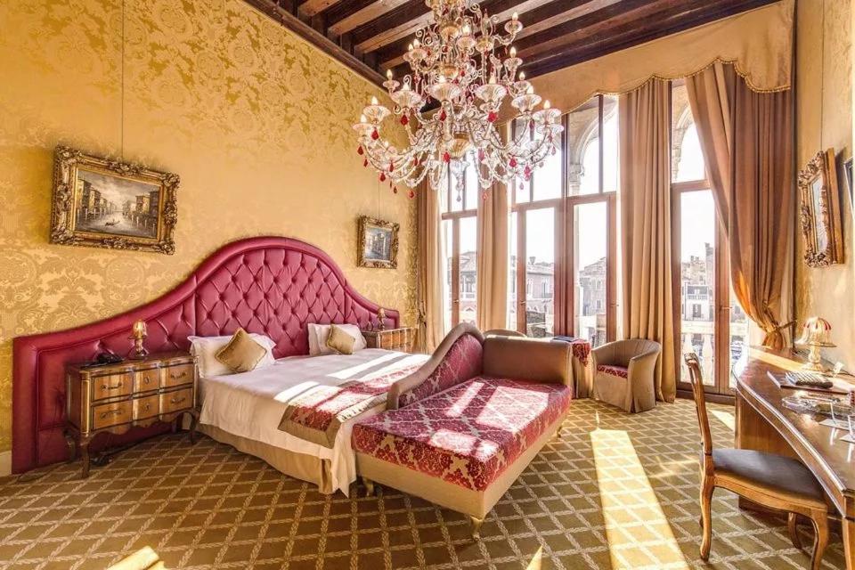 a bedroom with a large pink bed and a chandelier at Pesaro Palace in Venice